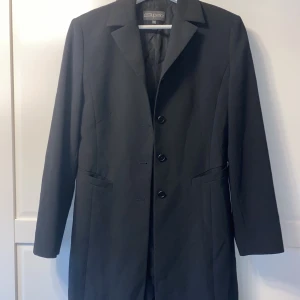 Lång kavaj/kort tunn kappa - En lite längre svart kavaj av märket Superior. Storlek 42 men passar som 36. Något figursydd. 