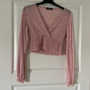 Blus - En rosa blommig blus med resår i midjan.