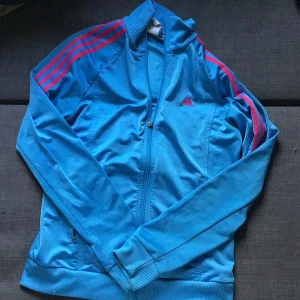 Adidas zip up - Adidas zip up med rosa linjer den har en konstig fläck på bild 2 och saknar dragkedja på alla dragkedjorna(fickorna)