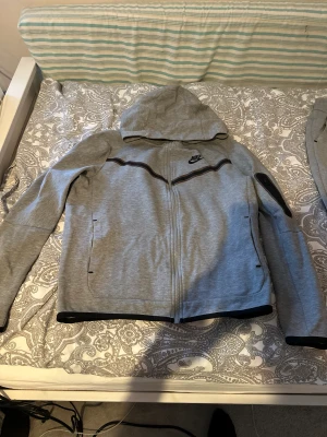 Grå Nike Tech Tracksuit  - Detta är en Nike tech tracksuit, väldigt varsamt använd och helt enkelt i riktigt riktigt bra skick. Köpt hela dressen för 1800kr, Vid fler frågor så är det bara att skriva👍