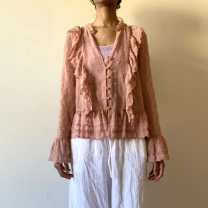 Rosa blus  - Säljer denna vackra sommar blus som knappt är använd, alla knappar finns kvar men ena bandet för översta knappen har gått sönder (lagas innan försäljning) färgen är gammal rosa och den är smyckad med volanger 
