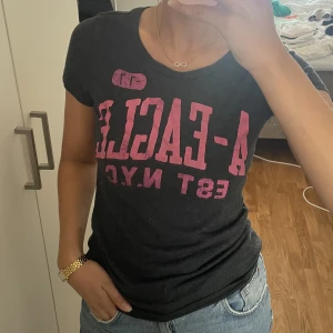 Grå T-shirt  - Grå T-shirt med rosa tryck. 