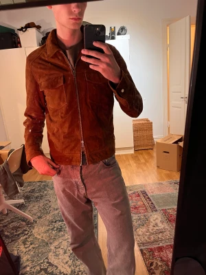 Mochajacka grand frank  - Elegant mochajacka från Grand Frank, tillverkad i Italien. Utförd i 100% getläder vilket ger den en lyxig känsla. Storlek medium. En tidlös investering, särskilt med tanke på sitt ursprungliga pris på 3600 kr.