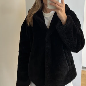 Pälsjacka - Fluffig mjuk pälsjacka (fake) med luva och knappar. Kort modell. Fint skick