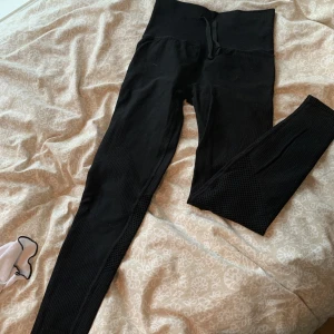 Träningstights - Träningstights från Hm,  helt nya med prislapp,  finns snören vid midjan ifall man vill knyta,  ficka vid ryggen,  ihåligt material nere vid bakre vaderna,  högmidjade.  Kan skicka fler bilder privat!   (Dom är ut och in på bilderna)