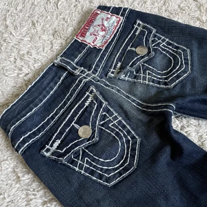 True Religion jeans - Vintage True Religion jeans. ❤️ Lågmidjad och smått bootcut/straight modell med snygga vita stygn. Innerben: 74cm, midja rakt över: 34cm. Är 165 som referens, kan fixa fler mått. 🫶 Håll koll på min profil, lägger för det mesta upp vintage jeans. 😍