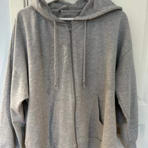 Grå zip up hoodie i oversize passform, sällan andvänd och är tunn i materialet.