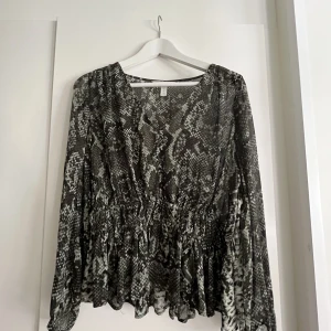 Blus  - Ormskinnsmönstrad blus från H&M. Endast använd ett fåtal gånger, och är i bra skick! Blusen är v-ringad och i ganska tunt material. 