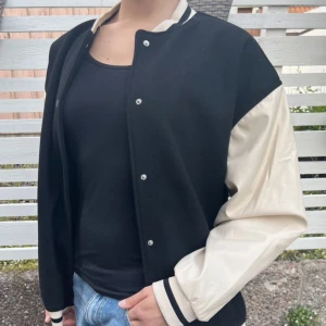 Varsity jacka - Collegejacka, oversize, svart/cremevit. HM divided. Perfekt höst/vårjacka! Väldigt varm. Nästan som ny, använd ett fåtal gånger. Funkar bra som temajacka för american highschool. Fler bilder och mått finns