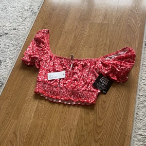 Topp i nyskick från Nelly. Com  - En röd vit blommig ofshoulder eller du kan ha den på axlarna du väljer i storlek S från Nelly 