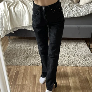 Jeans med slits - Svarta straightleg jeans med slits från Gina tricot. Högmidjade, sitter väldigt fint med en slits som går över skon! Något stor i storleken.