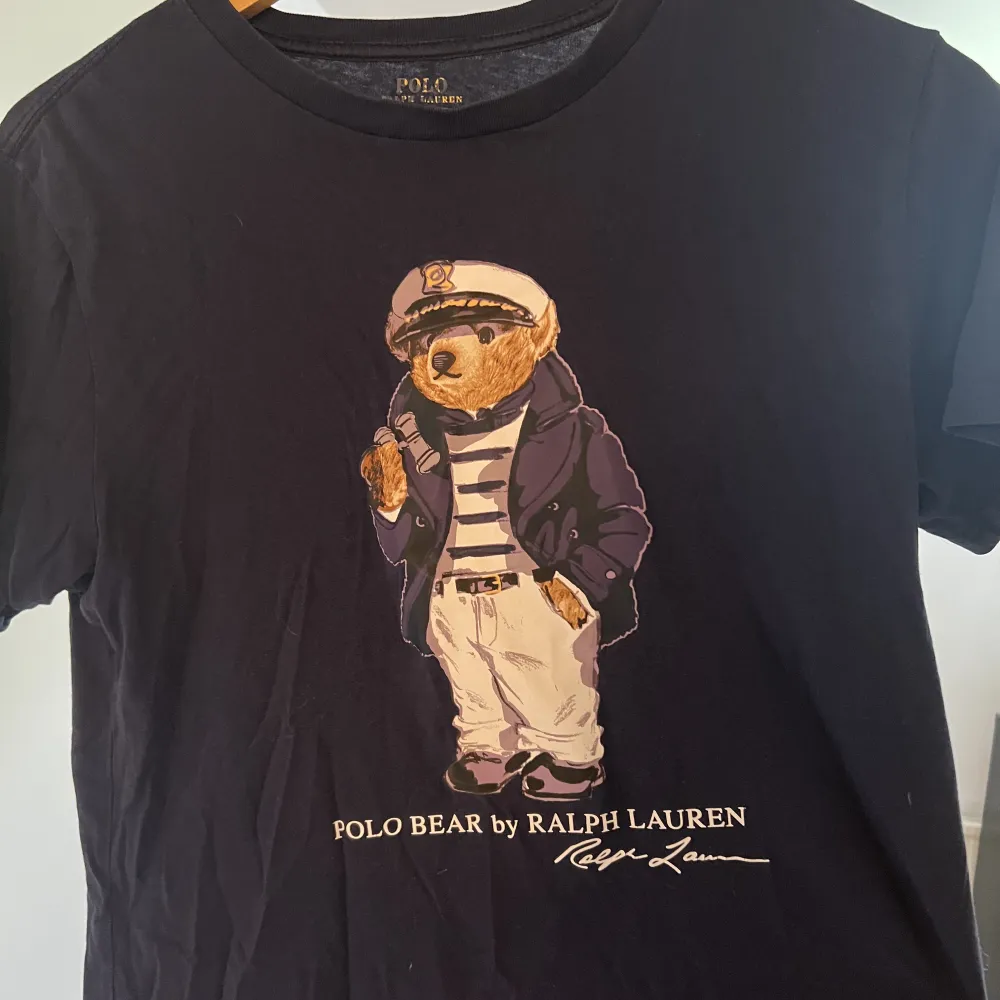 Mörkblå Ralph lauren t-shirt med en Björn på! Tröjan har används i ca ett år och skicket är 7,5/10 då den inte har några synliga defekter men har använts! Storleken är xs!😀nypris: 529 kr. T-shirts.