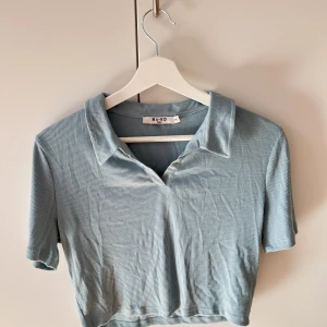 Blå t-shirt - Blå t-shirt i en kortare modell från NA-KD. helt oanvänd i storlek M.