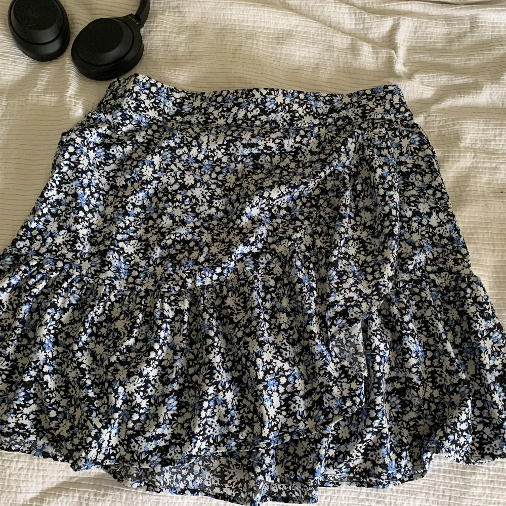 Svart, vit & blå blommig kjol från Lindex. Sparsamt använd. Den har resår bak i midjan så den är superskönt att ha på sig och är väldigt luftig och lätt.. Kjolar.
