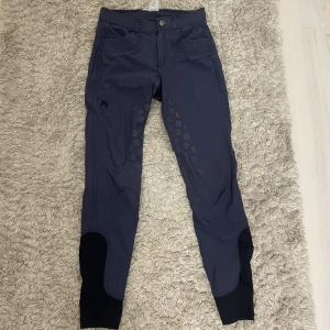 Jackson ridbyxor storlek 158/164 - Två par fina ridbyxor från Jackson, varit mina favoriter men tyvärr passar de inte längre. Marinblå och beiga men som är mer åt det gråa hållet. Använt de beiga på tävling och därav är grippet i lite bättre skick än de blåa. 300 för båda.