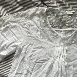 Vit top med spets - Vit top med genomskinlig spets, liten i storlek, ser genomskinlig ut på bilden men det är bara min bh färg.