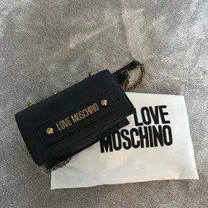 Super söt moschino väska som är köpt för cirka 3 år sedan. Kommer ej till användning längre. Svart med guldiga detaljer💓kommer med dustbag (pris kan diskuteras!!)