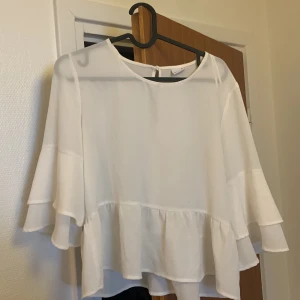 Vit blus  - En vit blus med volanger längst ner och på armarna, perfekt inför sommaren