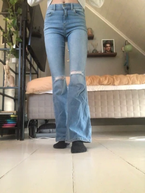 Jeans  - Bootcut jeans med hål på båda knäna. Mid-highwaist.