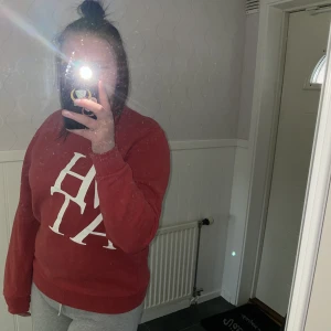 Sweatshirt  - Röd sweatshirt med text What. Storlek M.  