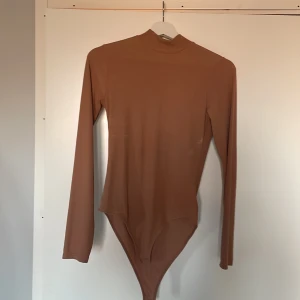Body - Beige/brun body från HM, använd 1/2 ggr dvs nyskick. Den är fint ribbad i luftigt tyg men inte genomskinligt.