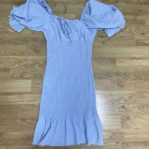Blå klänning - Blå klänning med puffärmar och volang.