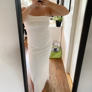 Vit långklänning med slits och en ärm - Vit långklänning med slits o en ärm från Boohoo. Storlek 44, endast använd en gång. 150kr plus frakt