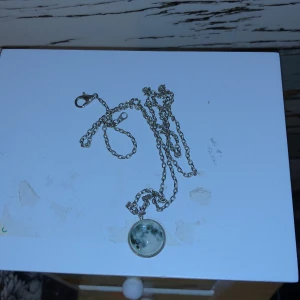 Halsband Måne - Ett väldigt fint, långt halsband med en måne som lyser i mörkret när det fått solljus på sig. Det lyser blått i mörkret