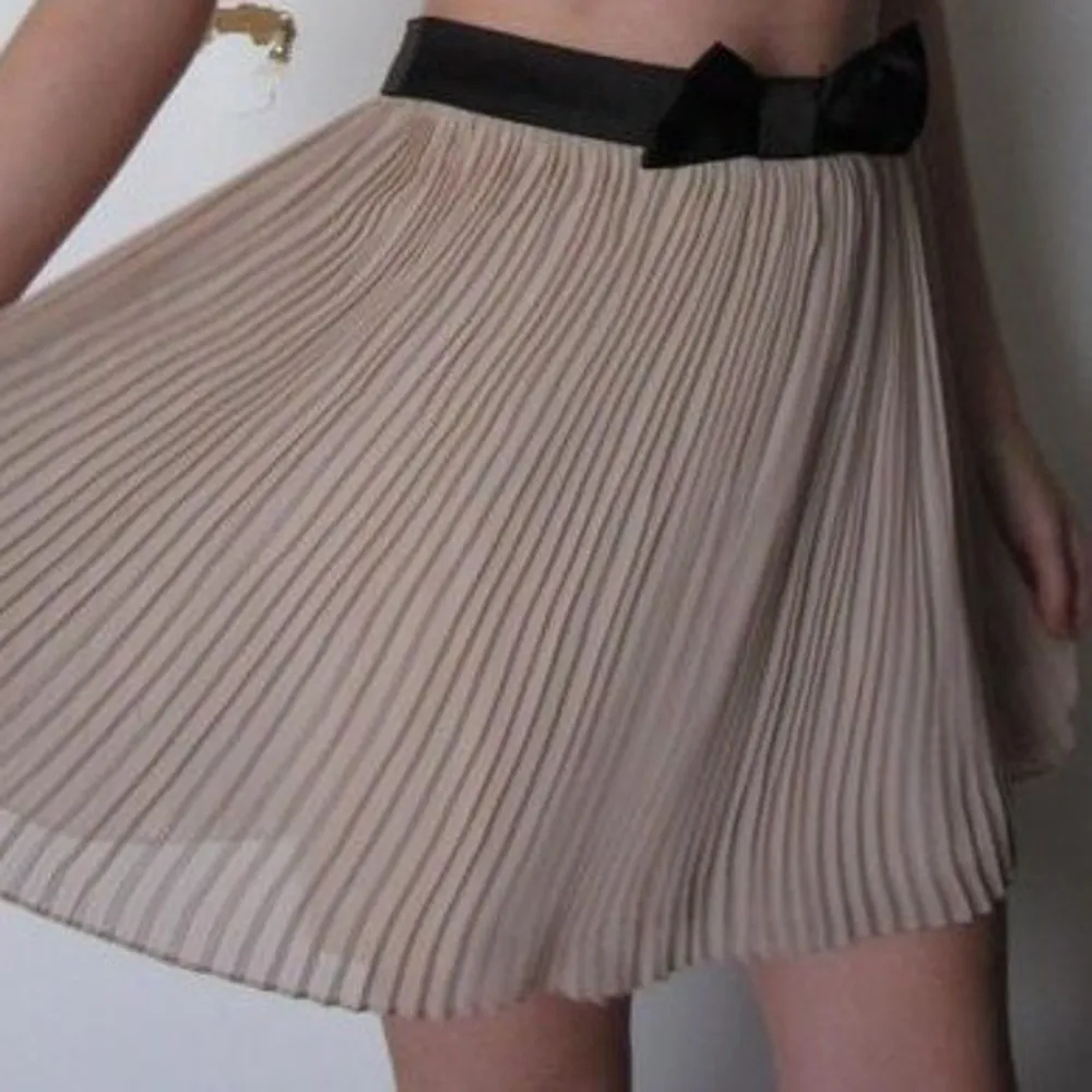 Söt plisserad kjol med svart rosett i midjan. Fint skick. Modellen på bilden är ca 168 cm lång och har 34/36. Kjolar.