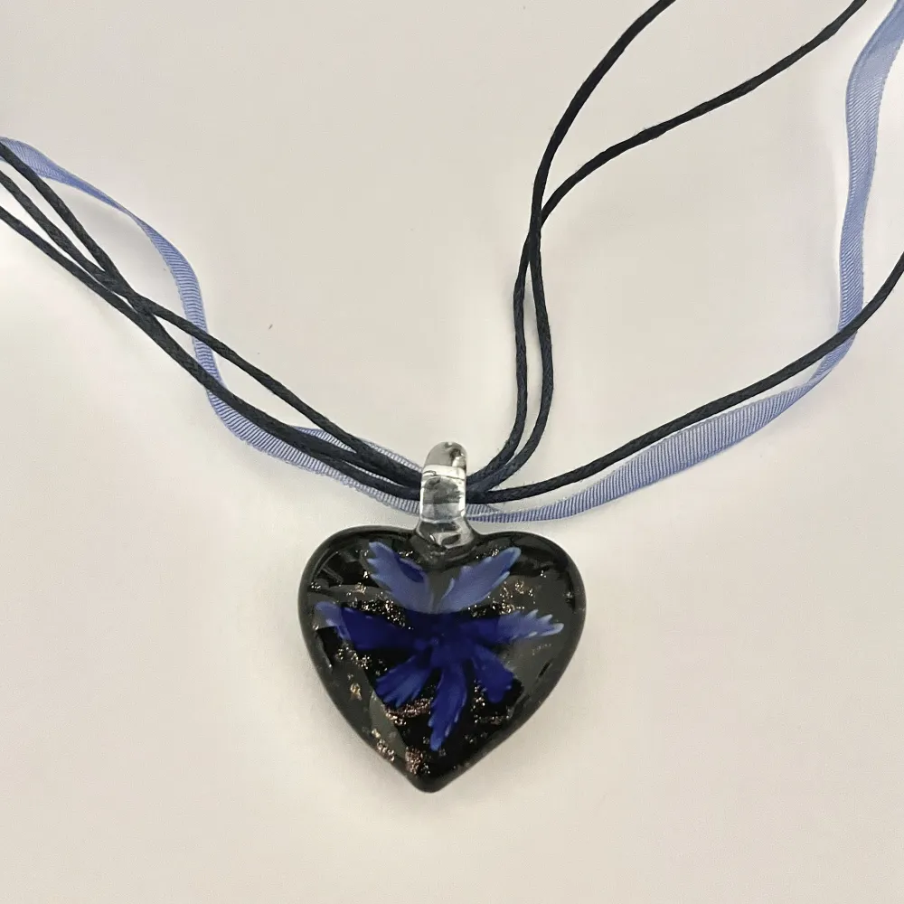 Blått halsband med ett hänge i glas i form av ett hjärta med en blomma i.. Accessoarer.
