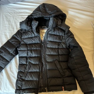 Vinterjacka Tommy hilfiger  - Varm jacka från Tommy Hilfiger. Passar till hösten, vintern och en kall vår. Köptes för 2000kr och använt mycket, dock har det inga slitningar. Finns sminkmärken vid kragen men kan tvätta bort det ordentligt innan det postas. Säljs för 400kr