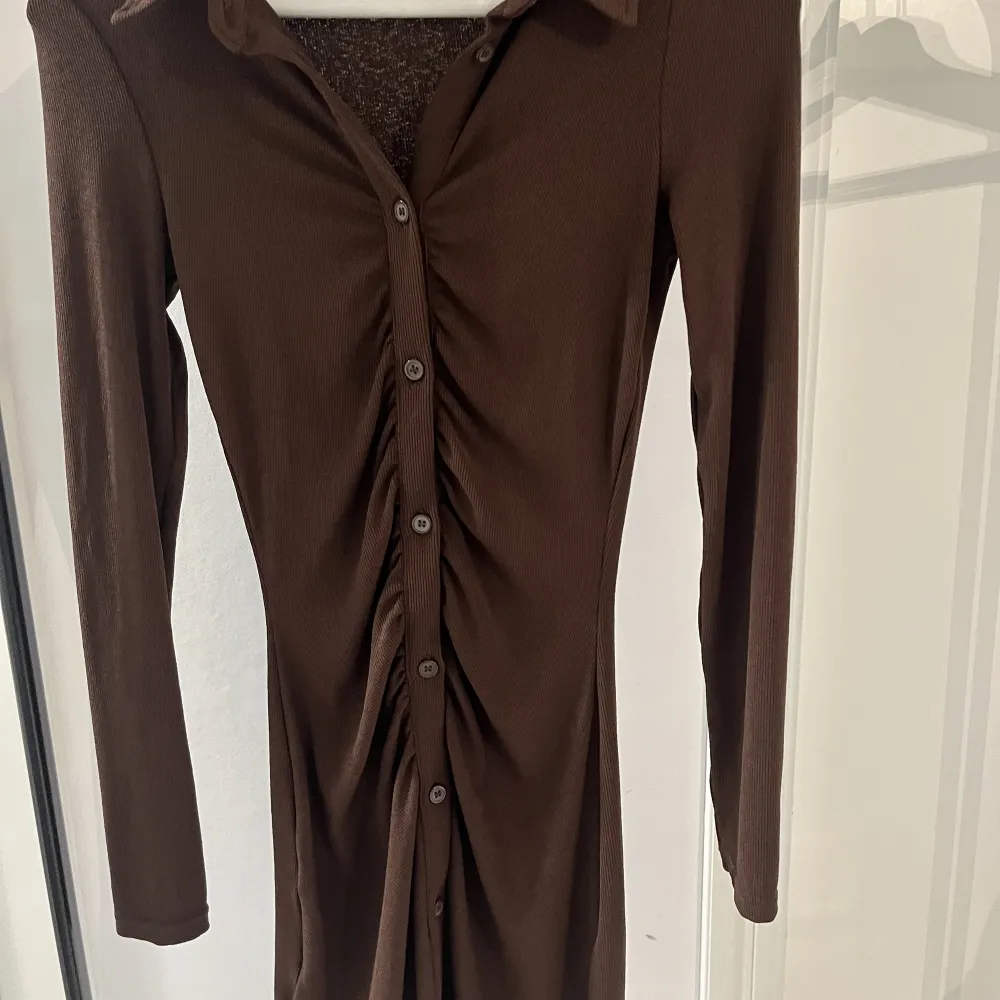 Denna bruna klänning är köpt på H&M och har ett ribbat material. Den har scrunch där framme som formar kroppen snyggt och går ner strax över knäna. Jättesnygg och har bra stretch. Den är XXS men kan passa någon med XS och S💗. Mekot.