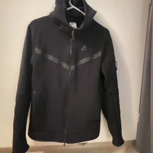 Nike tech kofta  - Säljer denna svarta Nike tech koftan därför jag känner att det inte är min stil längre. Storlek S i killmodellen som jag tycker är finare men sitter som en M.  Köpte för 1250 kr. Som ny inga skador. Pris kan diskuteras 