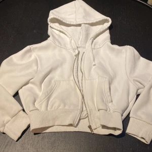  vit tjocktröja  -  det är en ganska kort vitt tjocktröja med dragkedja och fickor