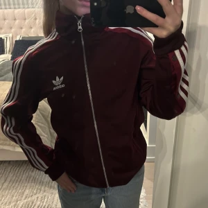 Vinröd adidas tröja/jacka - Supersnygg vinröd adidas tröja. Smuts på spegeln inte på tröjan!! Tröjan är i fint skick🙈 