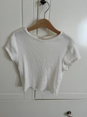 Söt topp - Söt kroppad T-shirt från Urban outfitters som är perfekt att ha under Cardigans eller att sova i. Den är tajt och smickrande, säljer pga att den inte kommit till användning.💖 Den är helt ren och i mycket fint skick, ett fint basis plagg som man ”måste” ha