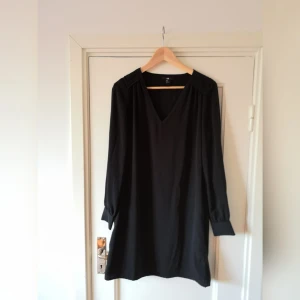  - Svart rak klänning. Flätad på axlarna 