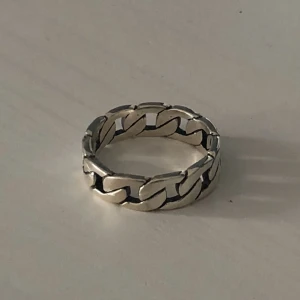  - En kedjering som har en omkrets på ca 7,5 cm och diameter på lite mindre än 2 cm! Är i silver och går att tvätta händerna och få vatten på utan att den tappar färg! 