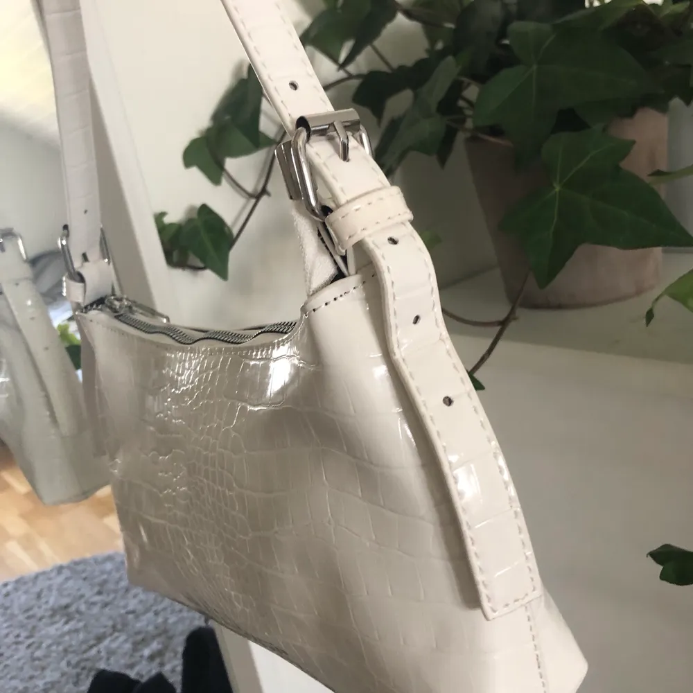 Vit väska med krokodilmönster. Väskan är helt ny, aldrig använd. Säljer pga har redan en liknande. Väskan har justerbara band. Passar perfekt att ha under armen. Ca 25cm på lång. . Laukut & Käsilaukut.