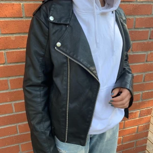 Fake svart skinn jacka med silvriga detaljer - Fin ”skinnjacka” med silvriga detaljer och fickor. Sällan använd pga att jag har flera liknande. Den är i XL men den passar till M, då de är jätte små i storleken. Du står för frakten:)