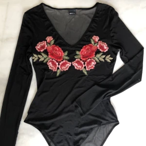 Body med broderidetaljer - Body med broderidetaljer från Gina Tricot. Använt skick, har blivit lite trådig på flera ställen. Frakten är inräknad i priset! 