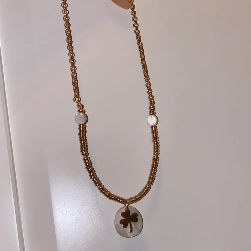 Ett rosé färgat halsband med vita pärlor och en treklövers symbol i mitten, jätte fin köpte den i sommras aldrig använt den har inte hunnit använda den.. Accessoarer.