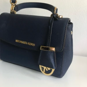 Michael kors väska - Väskan är ca 2 år gammal och i fint skick, fick den i födelsedagspresent. Tyvärr inget kvitto kvar. Kan frakta väskan mot kostnad men även mötas upp i Halmstad. Är inte säker på vad nypriset är men tror den är köpt för ca 1800kr då jag hittade en liknande väska på deras egna hemsida för 1800kr bara olika färger.  Betalning via swish https://www.michaelkors.eu/en_SE/en_SE/ava-extra-small-saffiano-leather-crossbody/_/R-32F5GAVC1L?color=0001