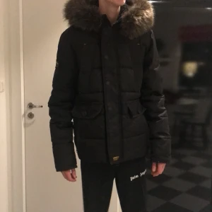 Superdry jacka - Jackan är använd i 2 månader, mycket fint skick. Fast luva med avtagbar fuskpälskant. På bilden bärs den av en kille som är 184 cm lång. Jackan är ganska liten i storleken. Köparen står för frakten. 