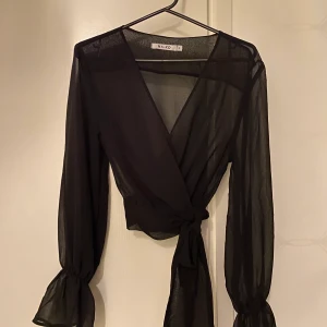 Svart blus från nakd  - Svart blus från nakd med knytning i midjan. Transparent, lika snygg med endast bh under som med ett linne. Strl XS. Croppad.