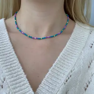 Flerfärgat pärlhalsband med små pärlor💙💚🦋💜🐢🤍 halsbandet försluts med lås och tråden är elastisk 
