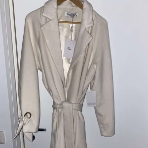 Kappa (Fest) helt ny strl 38 - Jättefin kappa i storlek 38 i fint material passar till lite finare tillfällen, aldrig använd ord pris 1000kr färgen är vit/beige. 