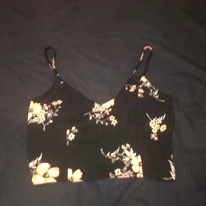 Blommig topp - Använd 1 gång men för liten. Sitter jättefint och skönt marierial. Knytning där bak se andra bilden 