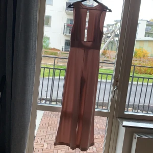 Rosa byxdress - Jättefin Byxdress med öppet mellan brösten och öppen mitt på ryggen. Vida byxben. Färgen är som den är på sista bilden😄😄  knappt använd 