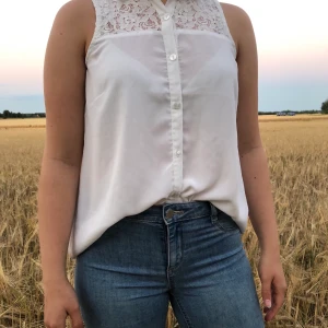 Vit blus med blommiga detaljer - Tuff blus med krage, blommiga detaljer och små knappar framtill.